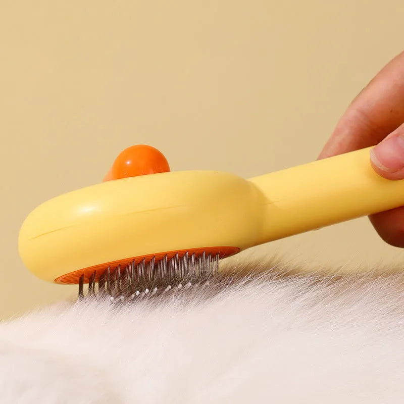 Small yellow duck-shaped pet grooming comb with needle tines for hair removal from cats and dogs.