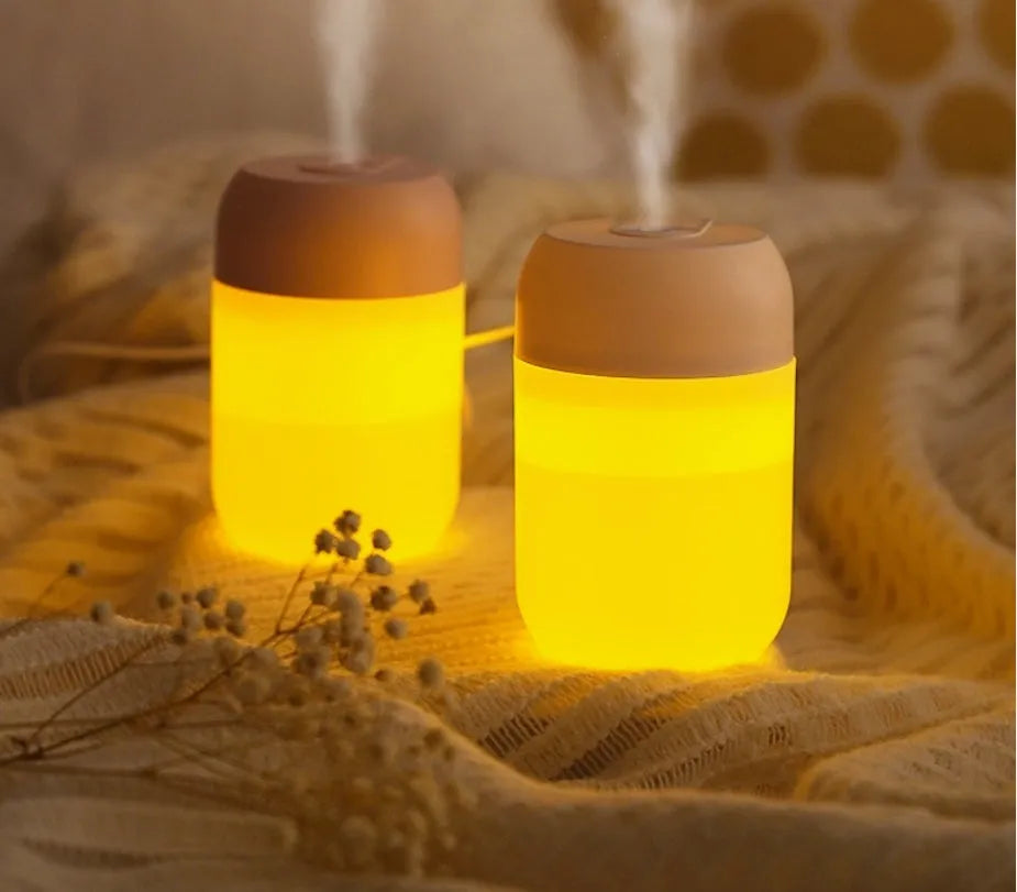 Small white cylindrical USB humidifier with aromatherapy diffuser on a wooden surface.