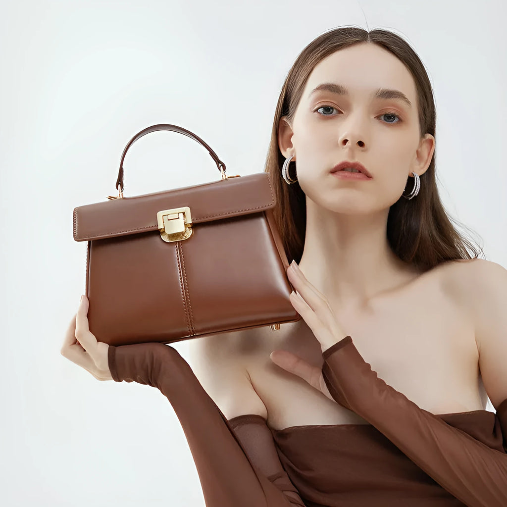 Women's black genuine leather shoulder bag with a clasp, shown with adjustable strap and open to reveal internal zippered pocket.