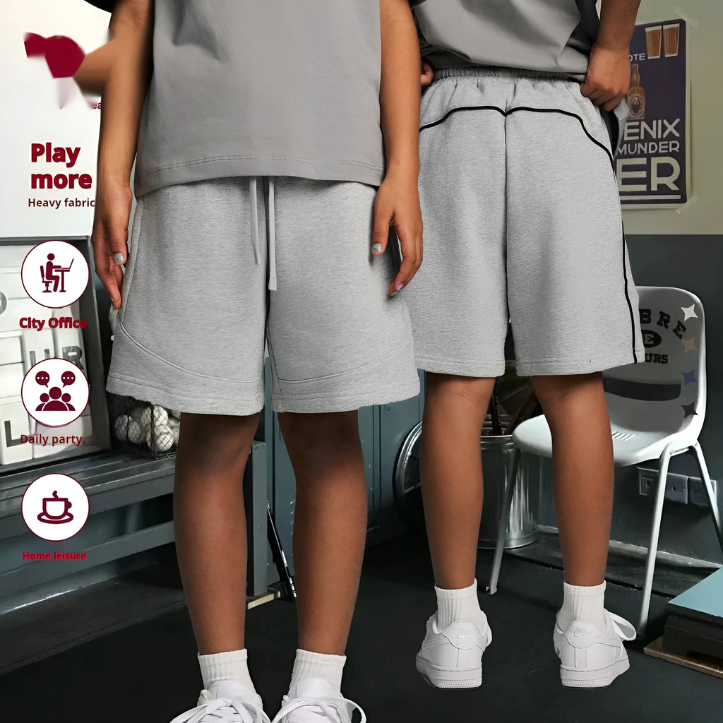 Child wearing solid colour loose cotton sports shorts in a neutral shade.