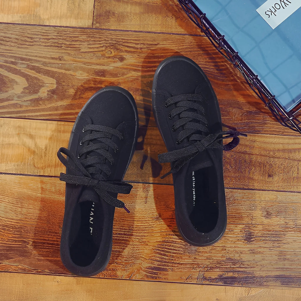 All black women's canvas lace-up work shoes with flat rubber sole on a white background.