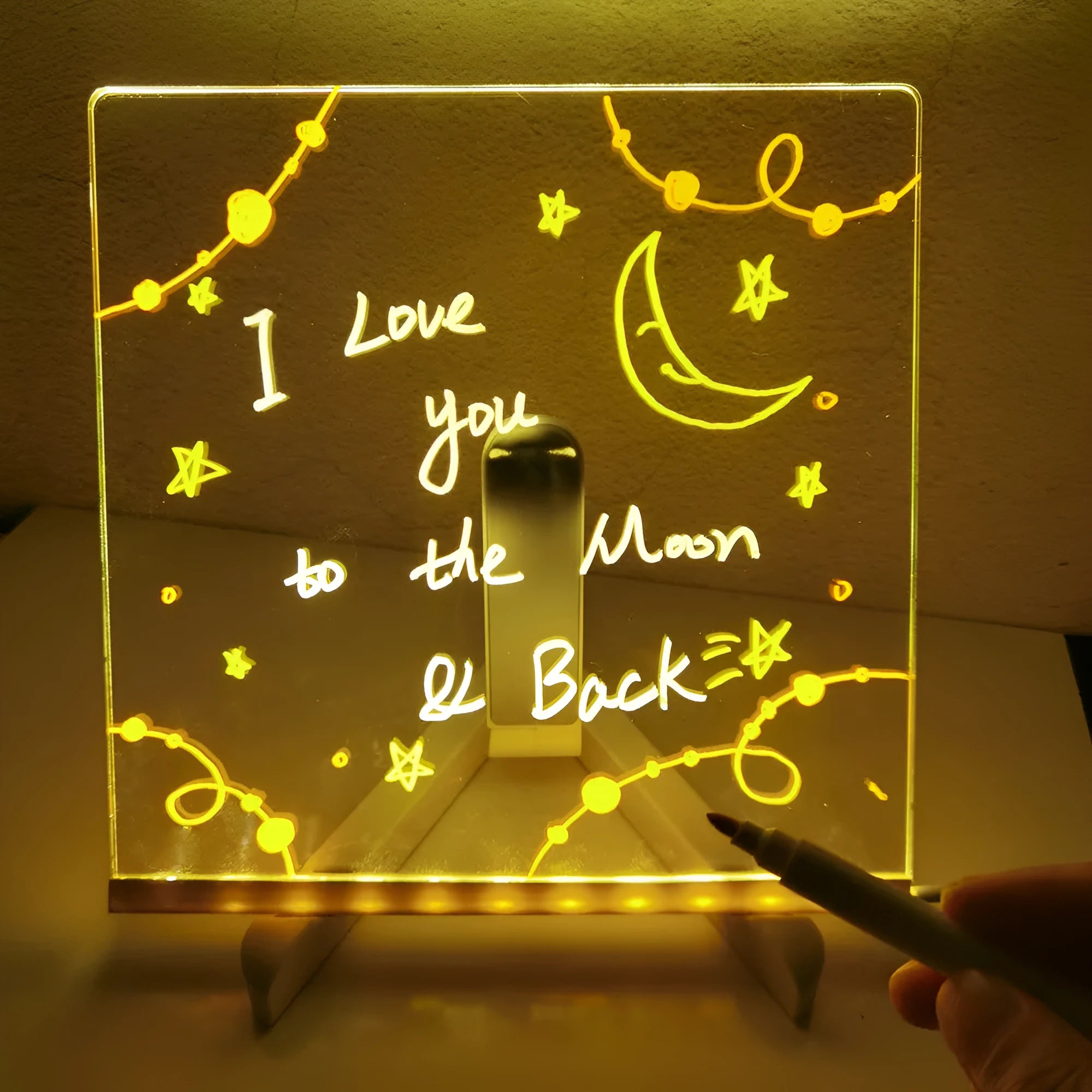 DIY acrylic LED message board on a desk with handwritten notes, glowing softly, next to colourful pens.