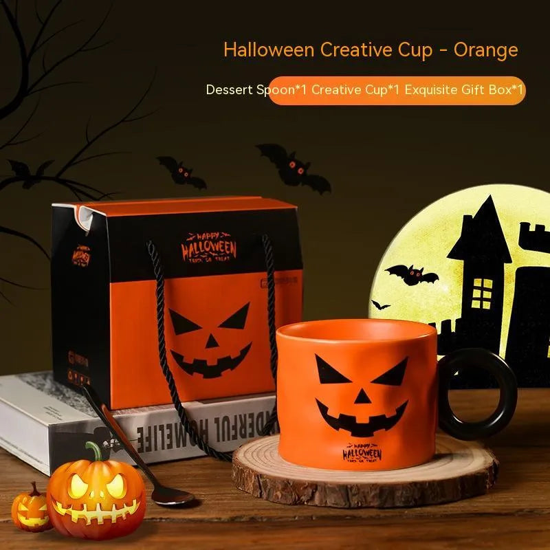 Orange ceramic pumpkin-shaped mug with handle on a table beside a dessert spoon and gift box.