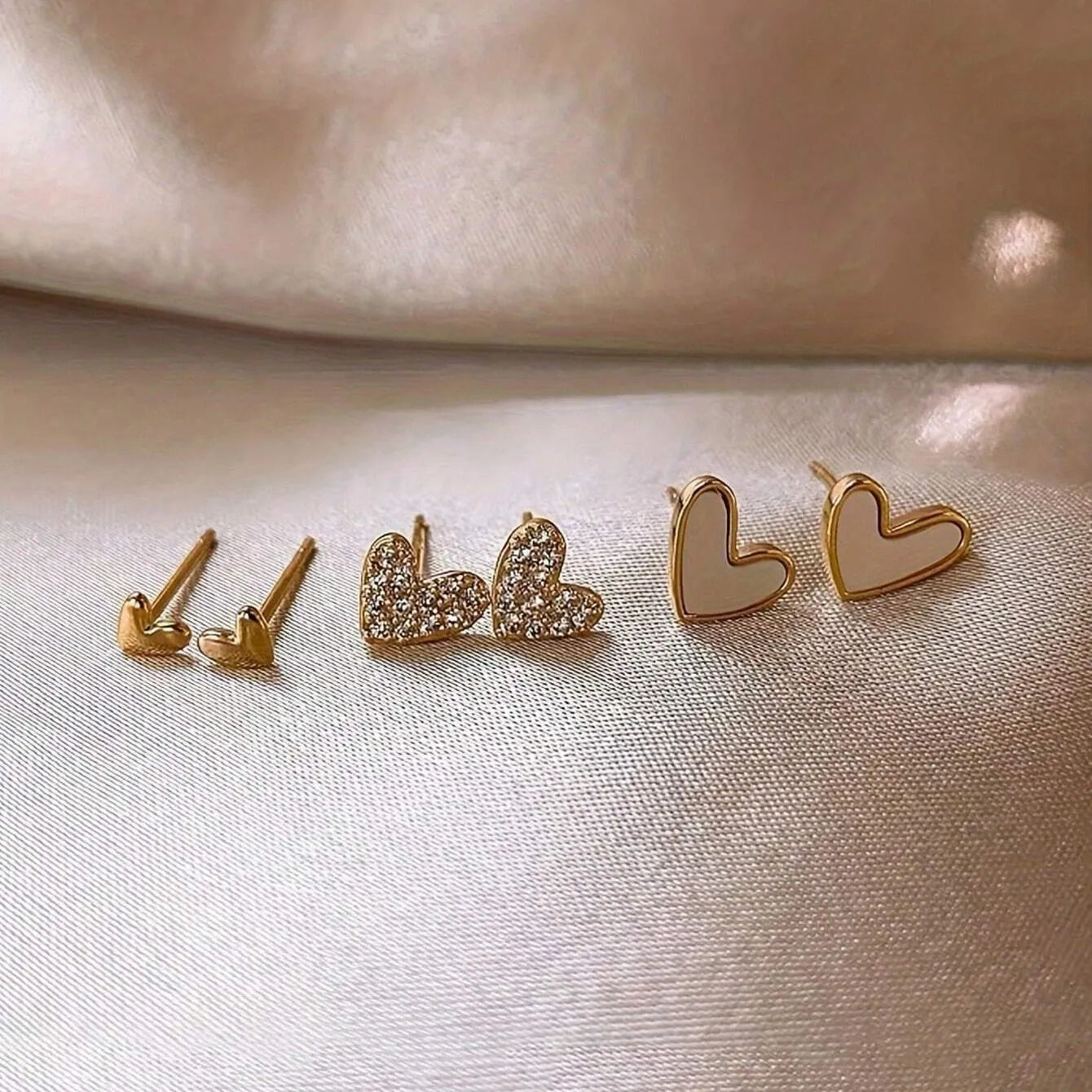 Three pairs of heart-shaped alloy earrings in gold, black, pink, and black-white colours
