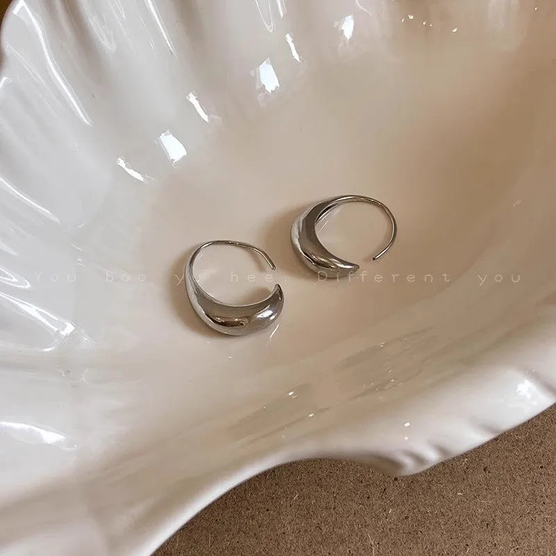 Teardrop hoop earrings in gold or silver tone alloy with C-shaped geometric design, one pair