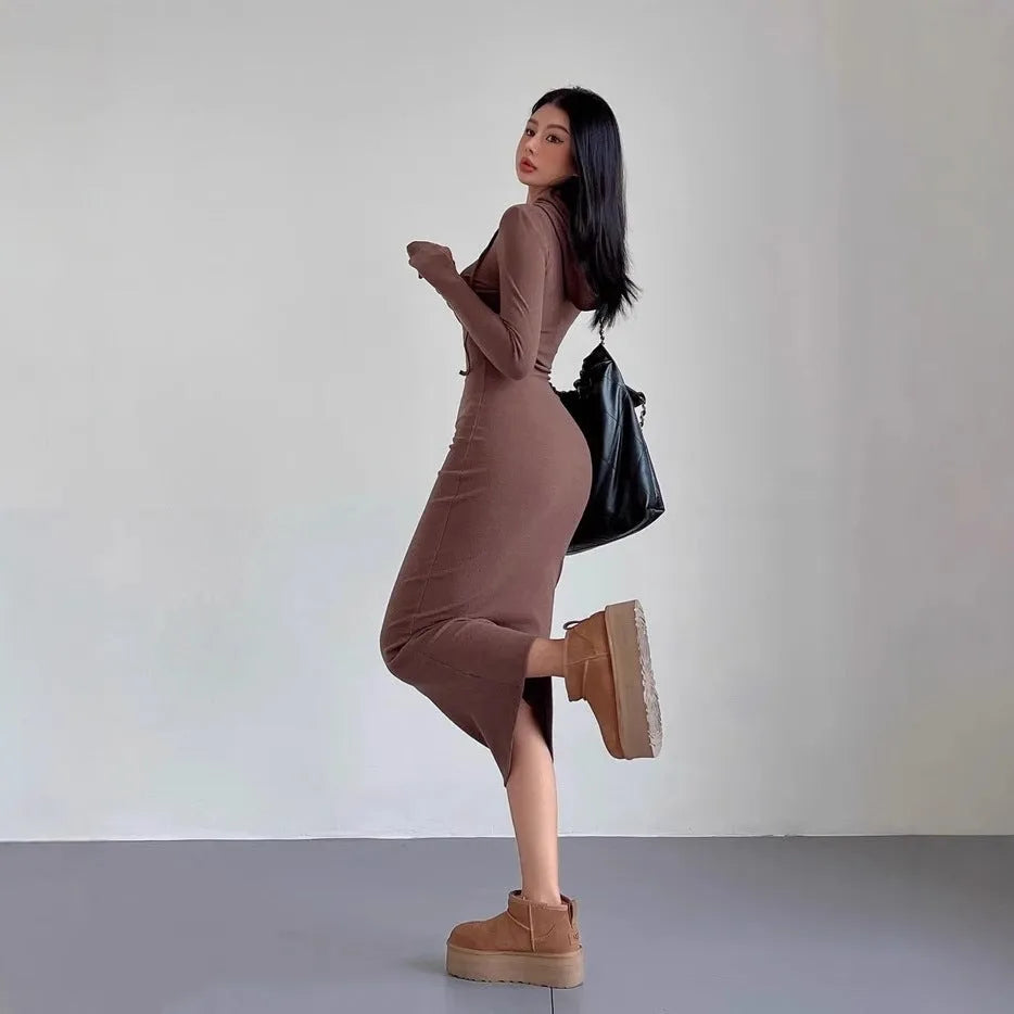 A woman modelling a grey hooded long-sleeve sheath dress with a high waist.
