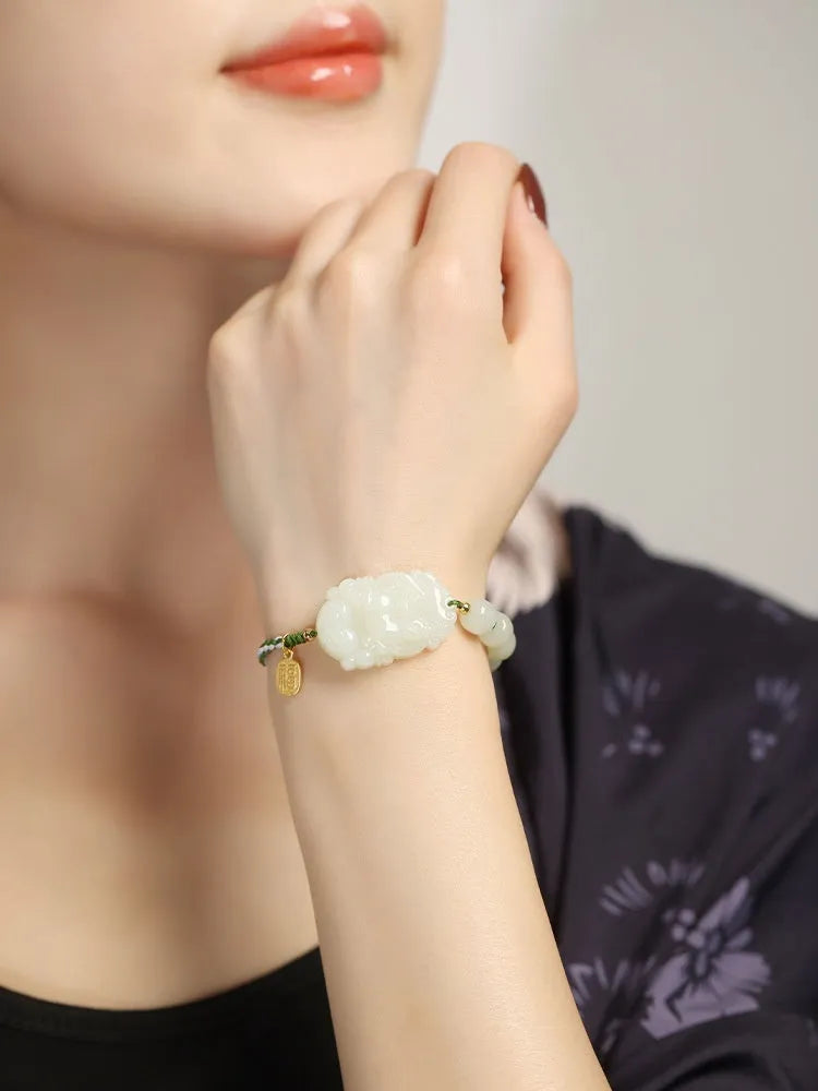 Hetian Jade Zodiac Bracelet on wrist showing rabbit charm, silver card, and red ice cotton rope.