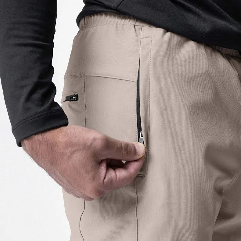 Man wearing dark grey loose-fit fitness trousers with tied ankle cuffs, made from quick-dry polyester fabric.