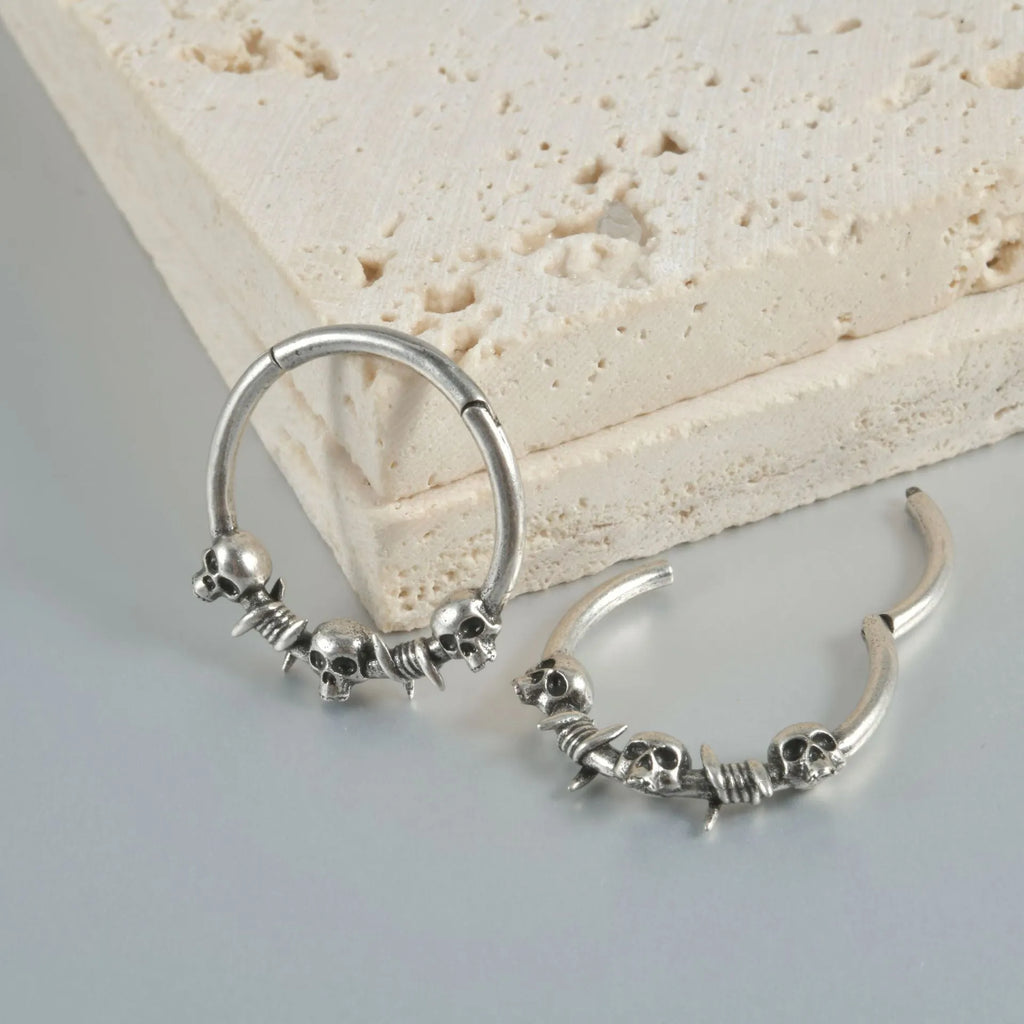 A pair of vintage-style copper earrings with an embossed ghost head design on a stud post, showing an antique silver finish.