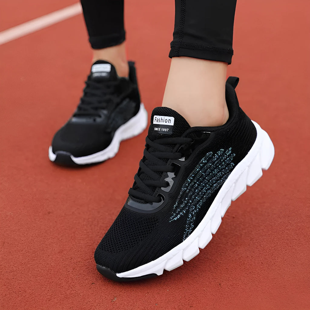 Low-top black and white running sneakers with cross-strap detail and flat MD sole.