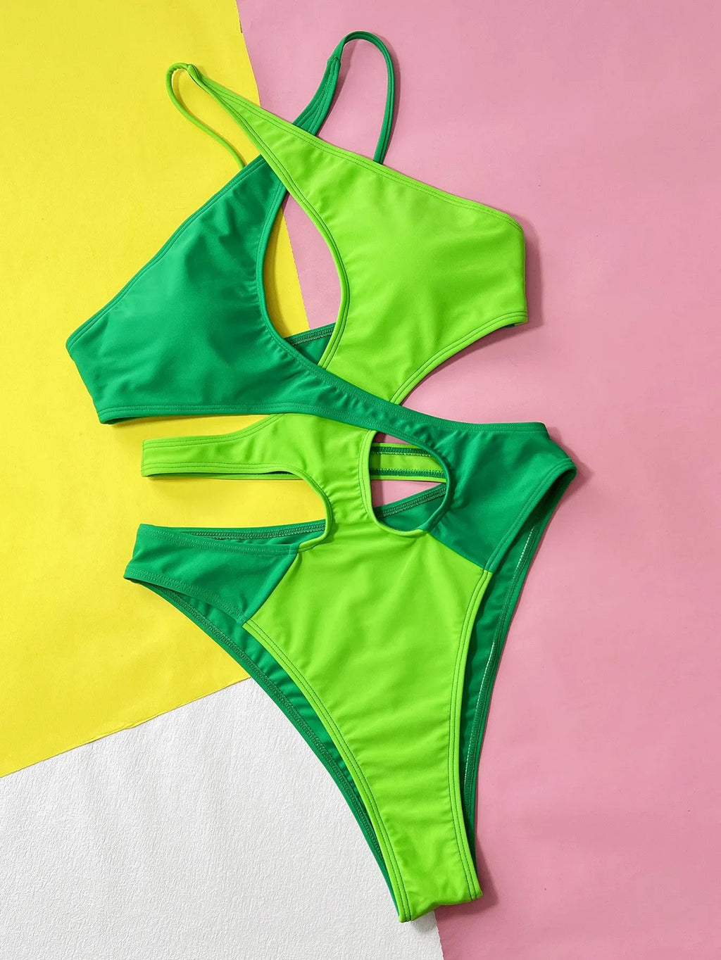 Green women's one-piece swimsuit with hollow contrast pattern on a mannequin.