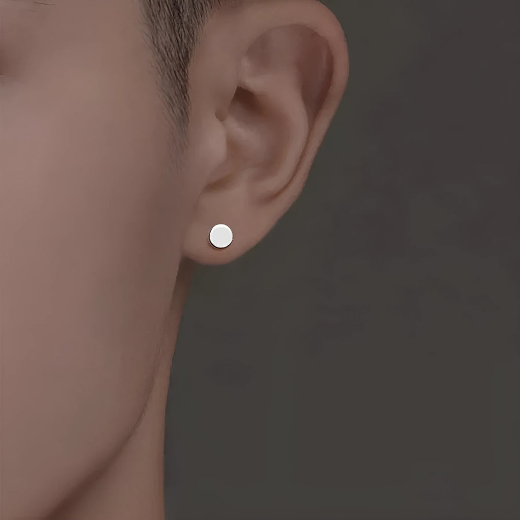 A pair of simple round flat stud earrings in sterling silver, shown in silver and black finishes.