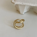 Geometric open ring with interlaced metal design and matte finish in gold colour.