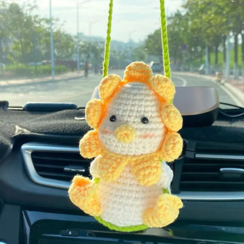Green and white crocheted wool car plant decoration with a white hanging rope.