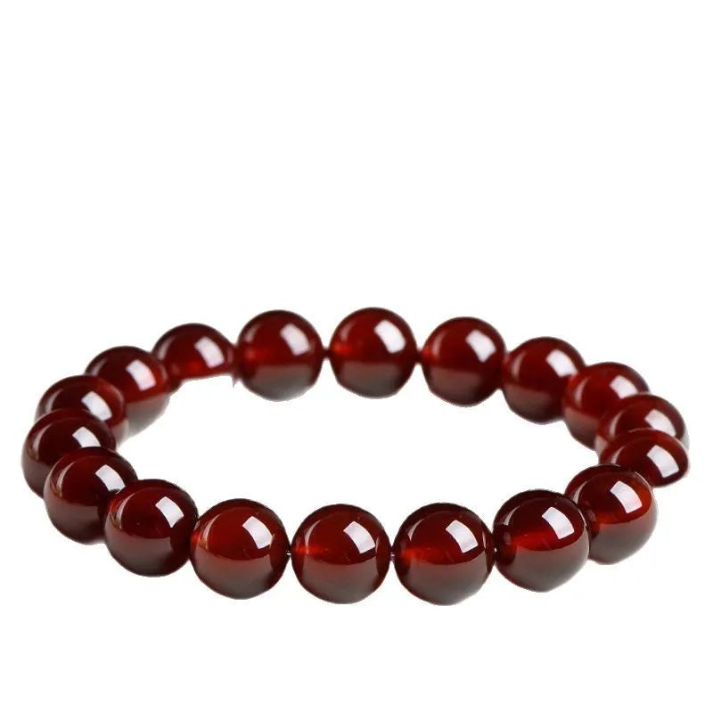 Natural orange red garnet ball bracelet with a silver Ruyi charm on a white background.