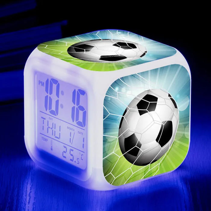 Square cartoon football pattern children's alarm clock with mute alarm on a bedside table.