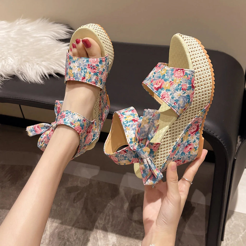 Women's wedge peep toe sandals with an ankle strap buckle in a floral pattern.