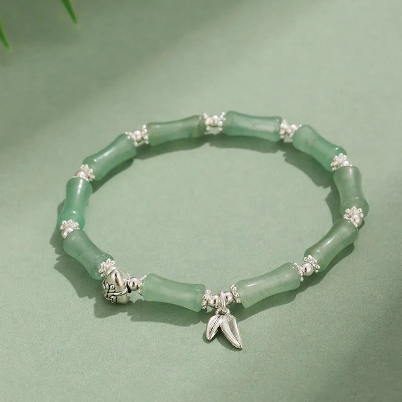Women's green aventurine crystal bracelet with bamboo, strawberry quartz, and jade beads on wrist.