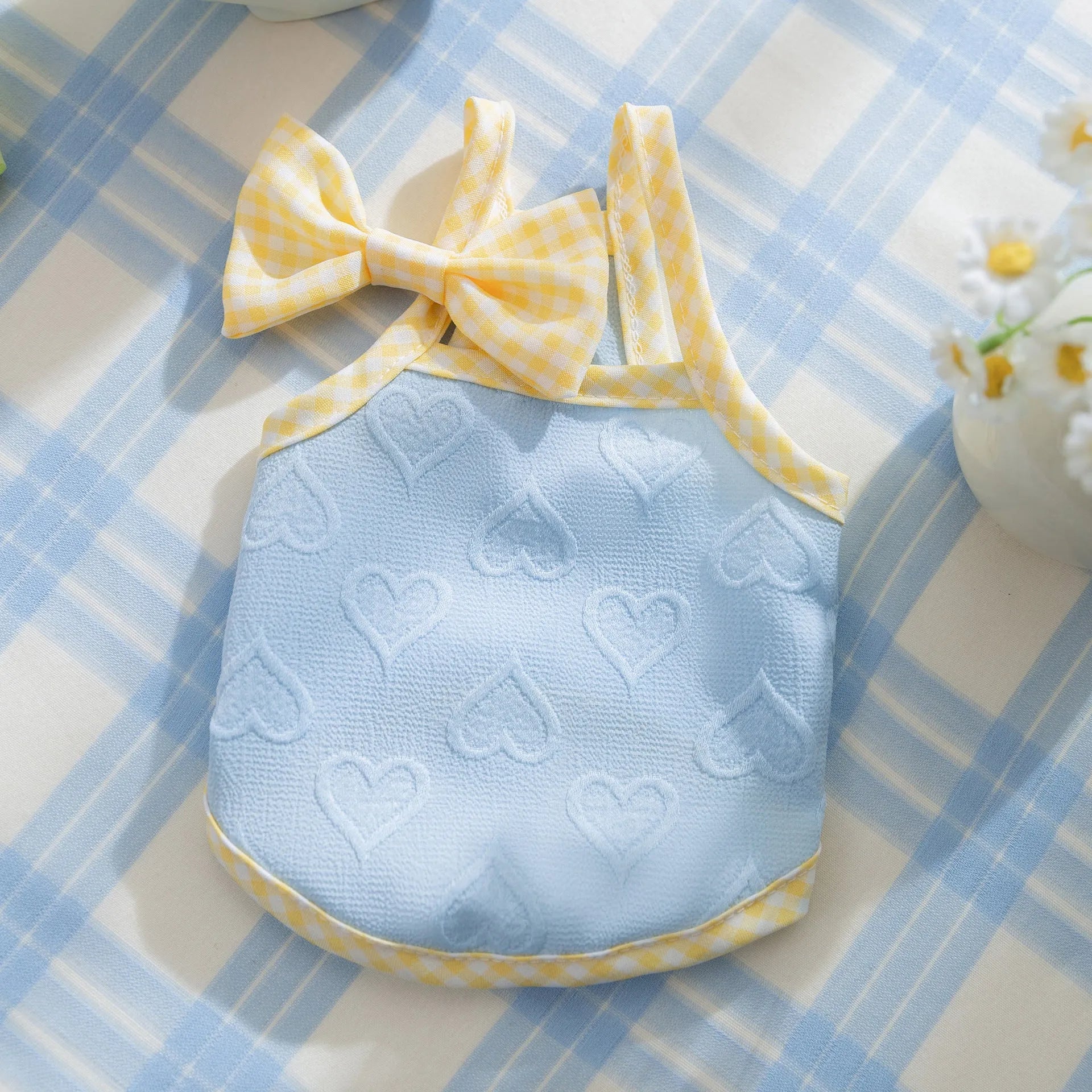 Small dog wearing a blue elastic vest with a bow and heart texture on the suspenders.