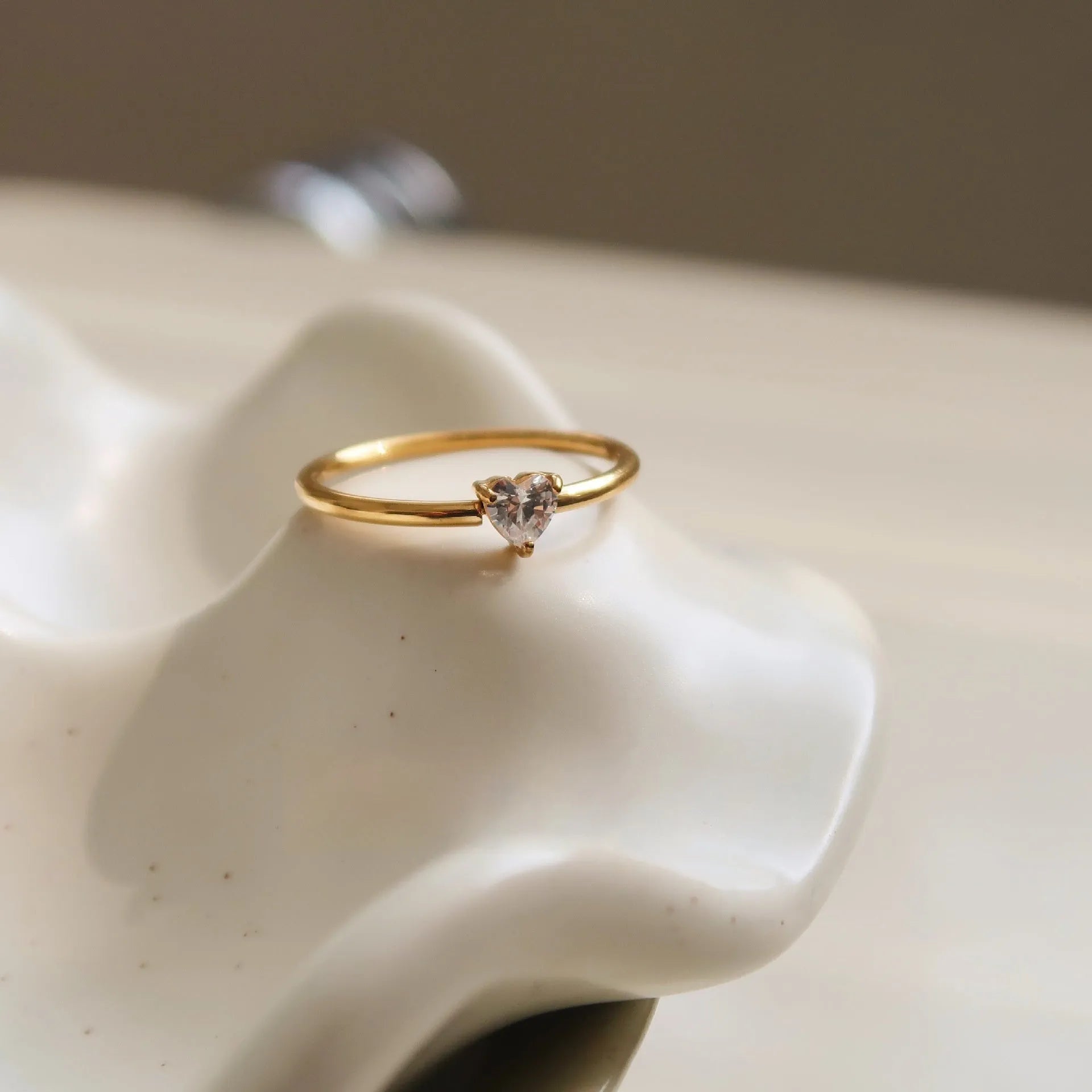 Golden heart-shaped stainless steel ring with electroplated finish shown in UK sizes 5-8