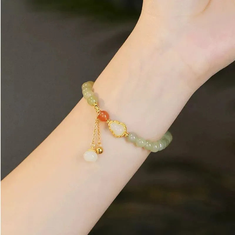 Qingshui jade women's bracelet with gold plated beads and a fu character charm.
