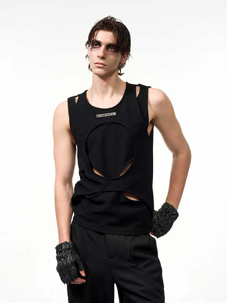 Man wearing a loose-fitting black sleeveless hollow thread waistcoat over a white t-shirt.