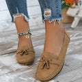 Women's suede flat shoes with a bow detail in pink, shown from the side on a plain background.