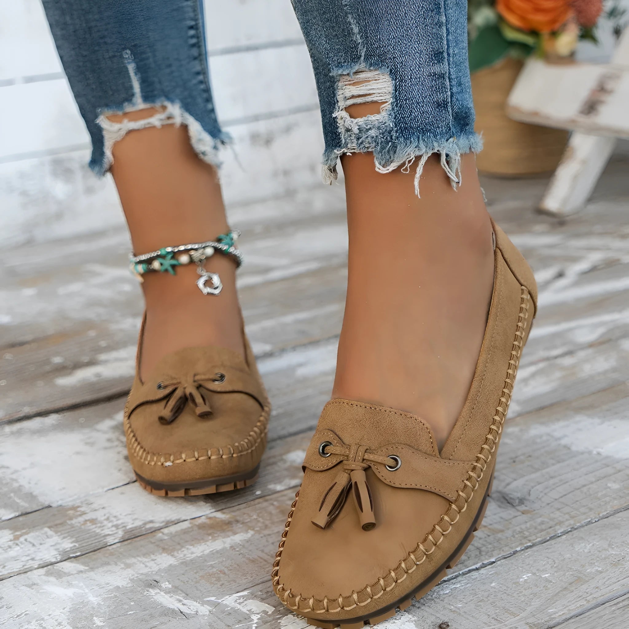 Women's suede flat shoes with a bow detail in pink, shown from the side on a plain background.