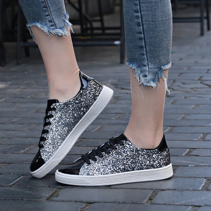 Women's black, gold, and pink sequinned low-top lace-up shoes on a white background.