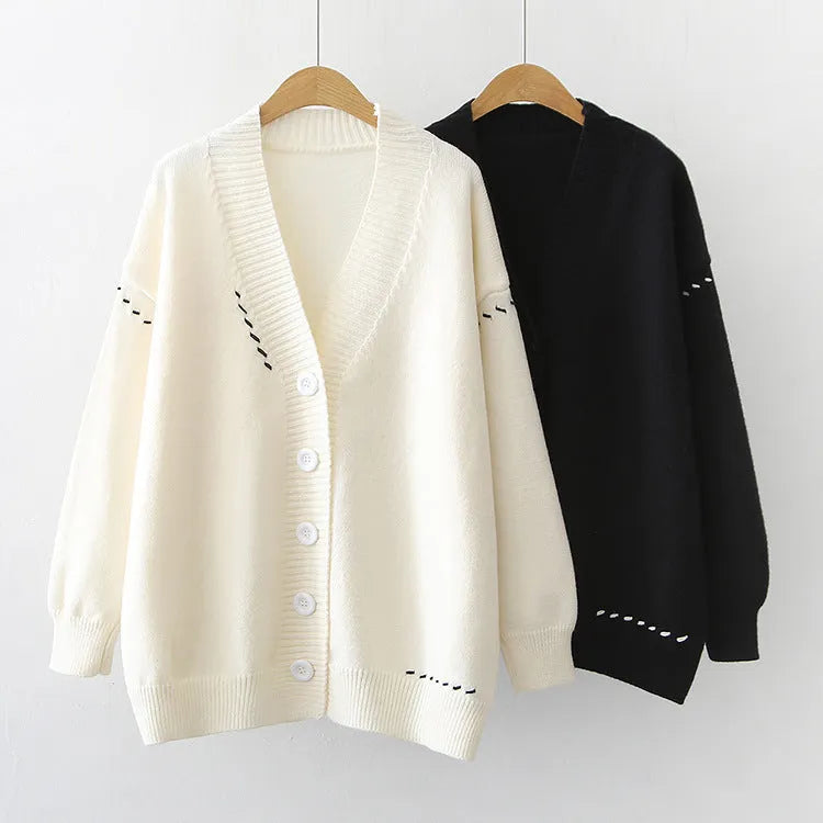 Women's loose-fit knitted cardigan coat in black or white, showing long sleeves and solid colour.