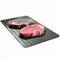 Black aluminium fast defrost tray for thawing frozen food on a kitchen counter.
