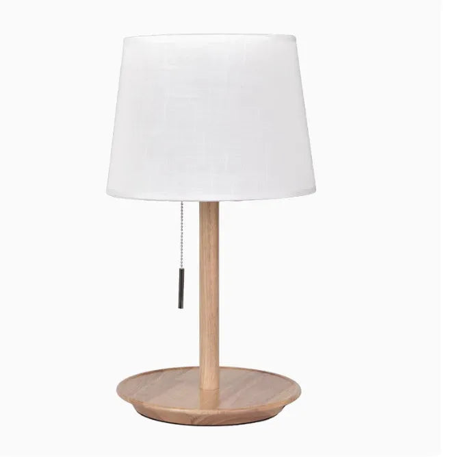 Walnut coloured solid wood bedside lamp with a white fabric lampshade and a cable switch