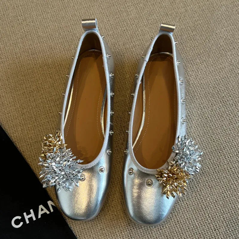 Women's silver Mary Jane loafers with flower rivets, buckle strap, round toe, and flat rubber sole.
