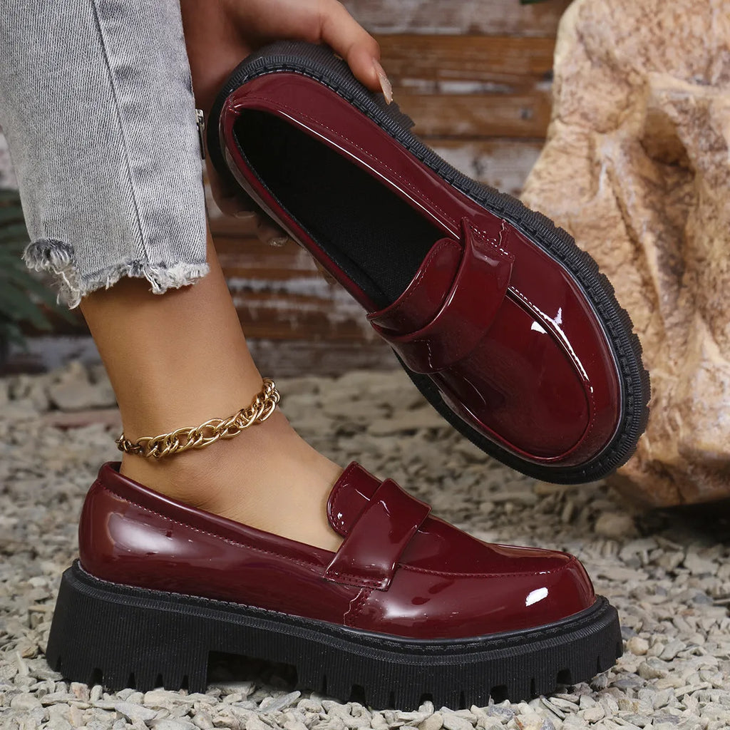 Women's black slip-on loafers with a chunky rubber sole and thick platform heel.