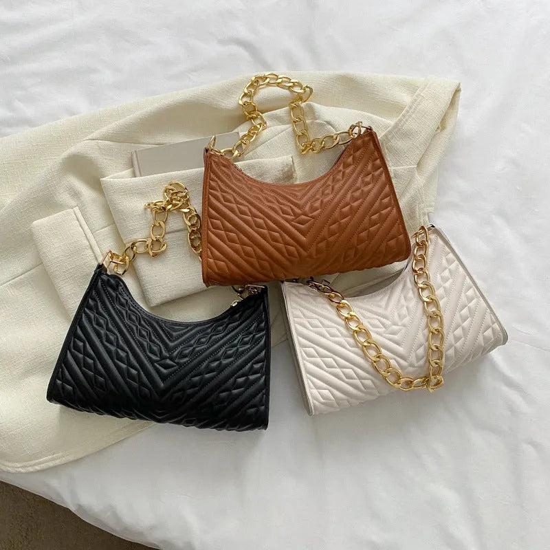 A structured black pleated women's shoulder bag with a chain strap and a soft handle, showing its square shape.