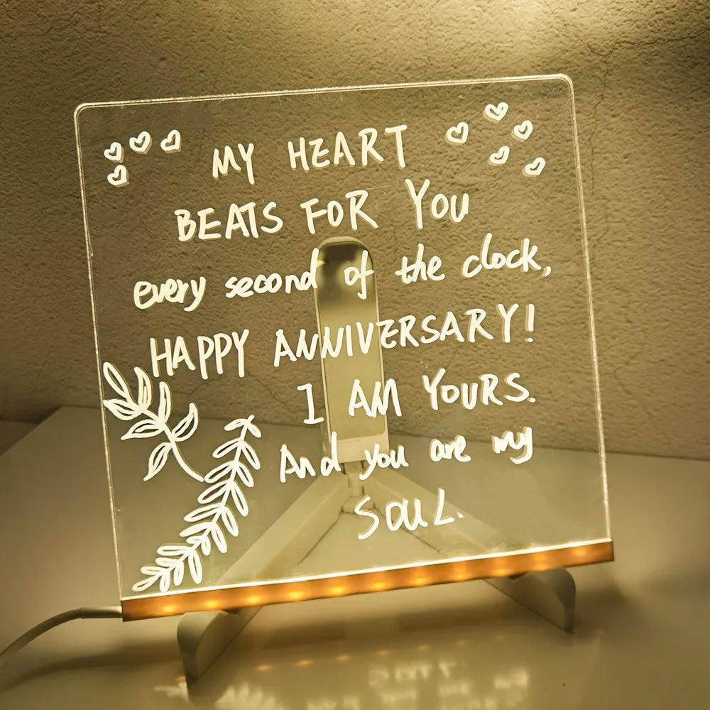 DIY acrylic LED message board on a desk with handwritten notes, glowing softly, next to colourful pens.