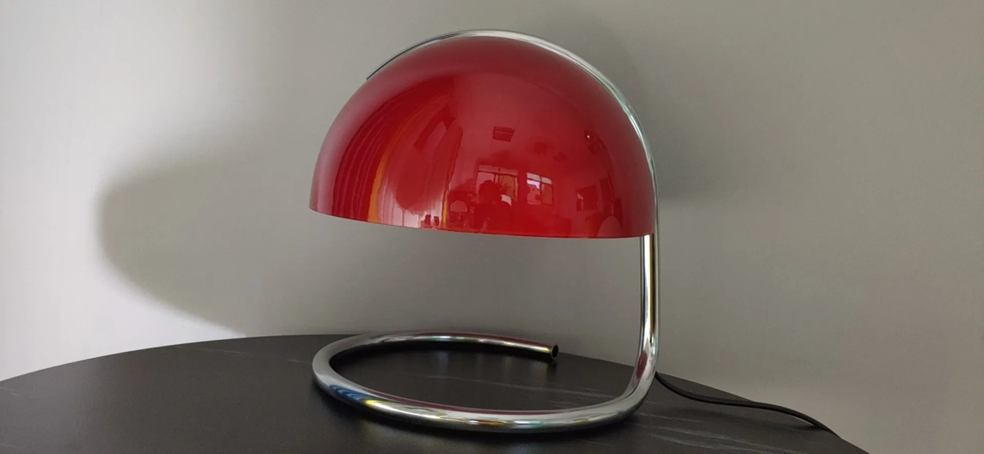 Retro metal mushroom table lamp with three-colour light in orange finish on a bedside table