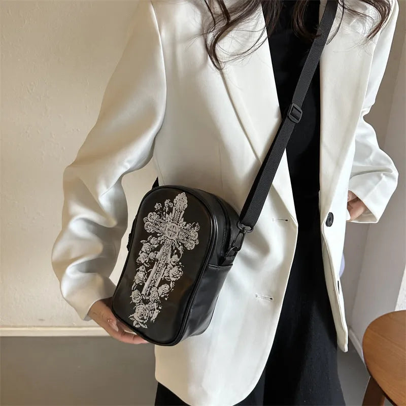 Black Halloween crossbody bag with orange pumpkin, white ghost, and black bat graffiti print, shown on adjustable strap.