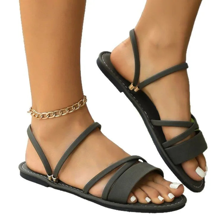 Women's flat sandals with cross strap and flip-toe buckle in black, brown, or green