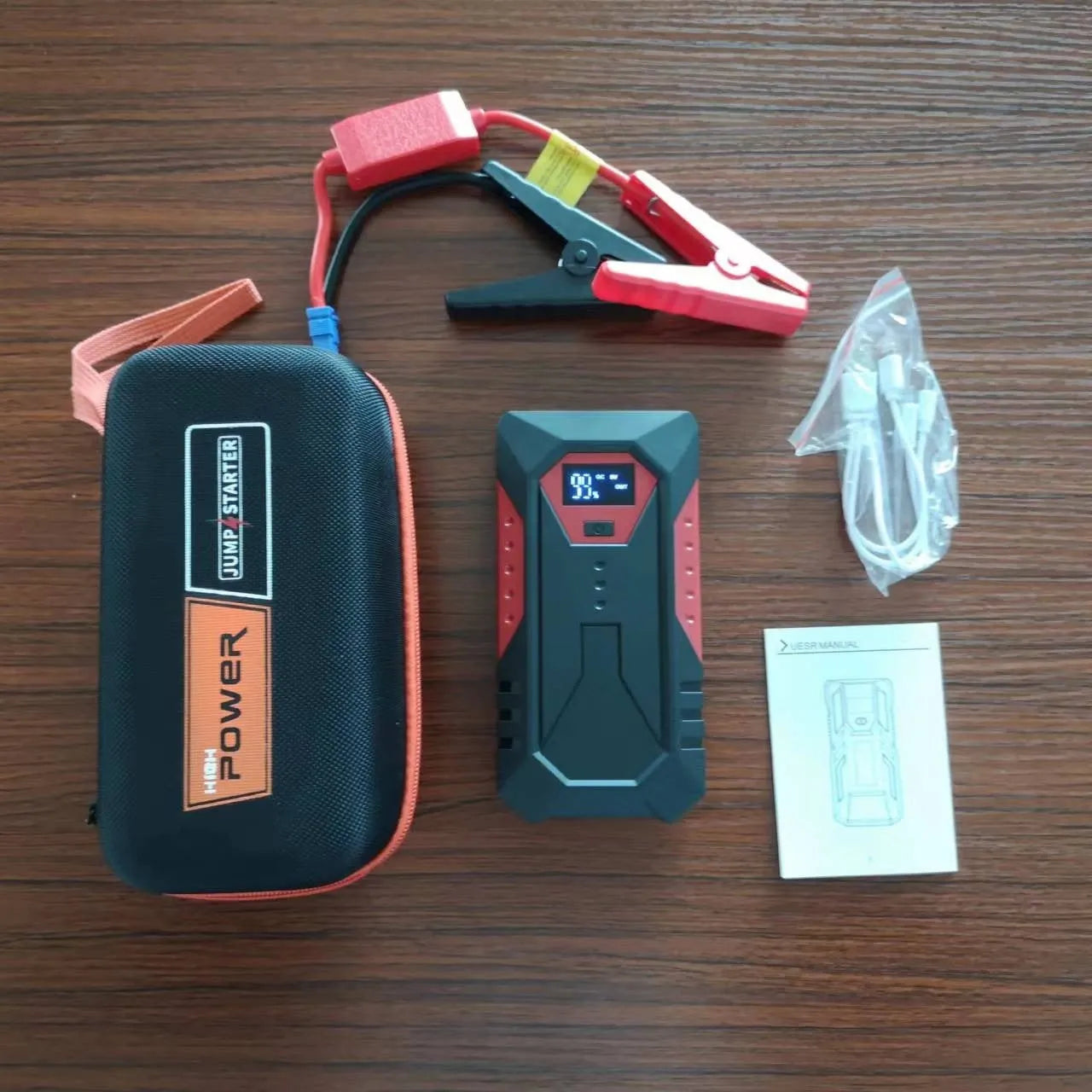 Red 12V car emergency jump starter power bank with battery clamps and charging cable