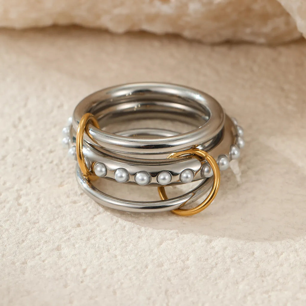 Stacked stainless steel rings with 18K gold plating in multiple colour options on a woman's hand.