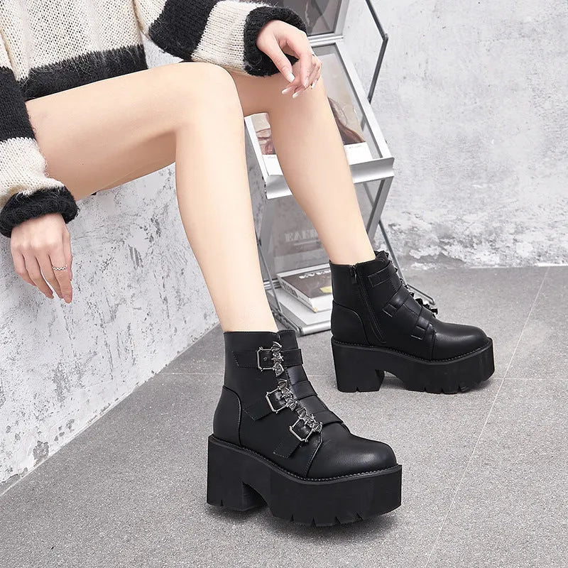 Black women's punk ankle boots with metal bat buckle and thick platform sole.