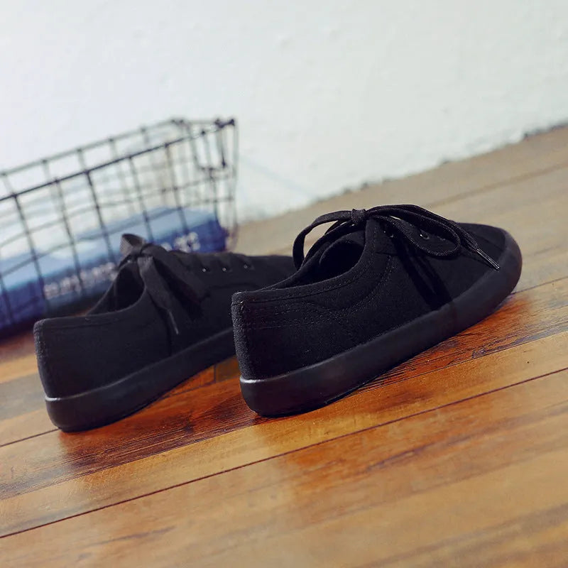 All black women's canvas lace-up work shoes with flat rubber sole on a white background.