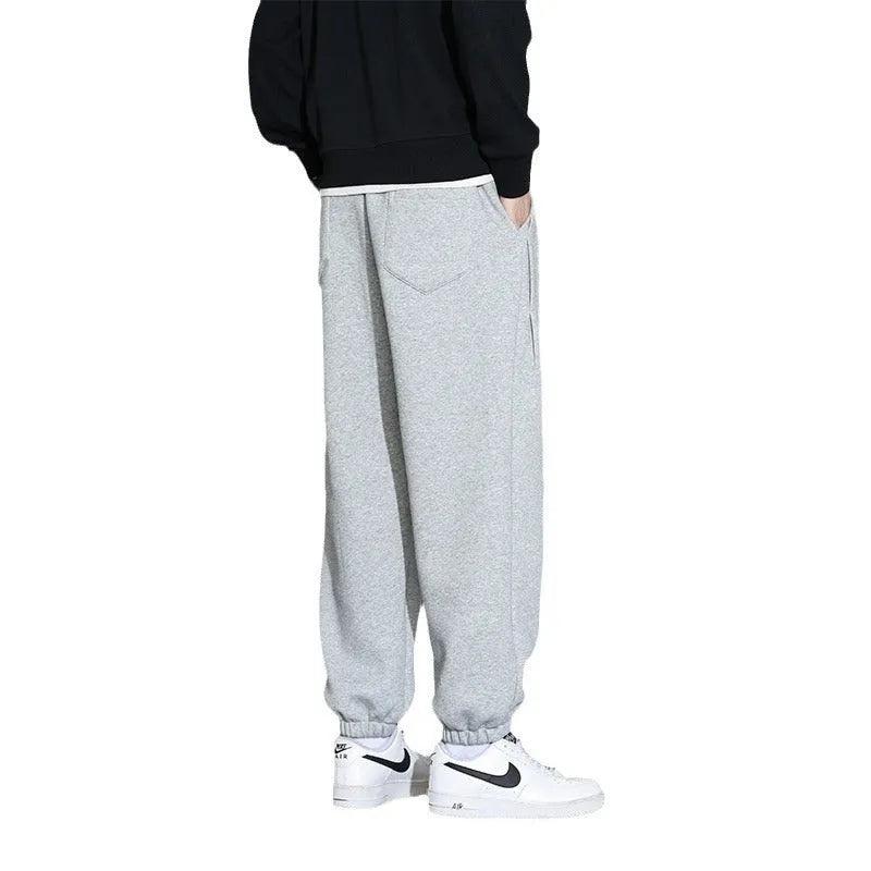 Men's loose grey cotton blend sports trousers with a drawstring waist on a hanger.