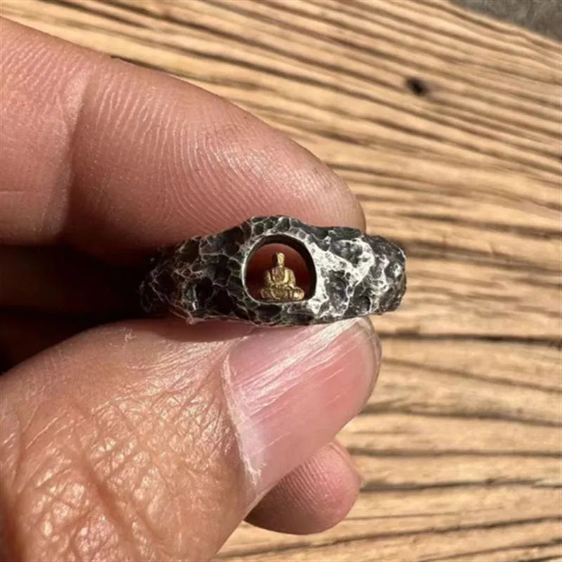 Close-up of a hand-forged copper ring with a rock texture and a carved Buddha design.