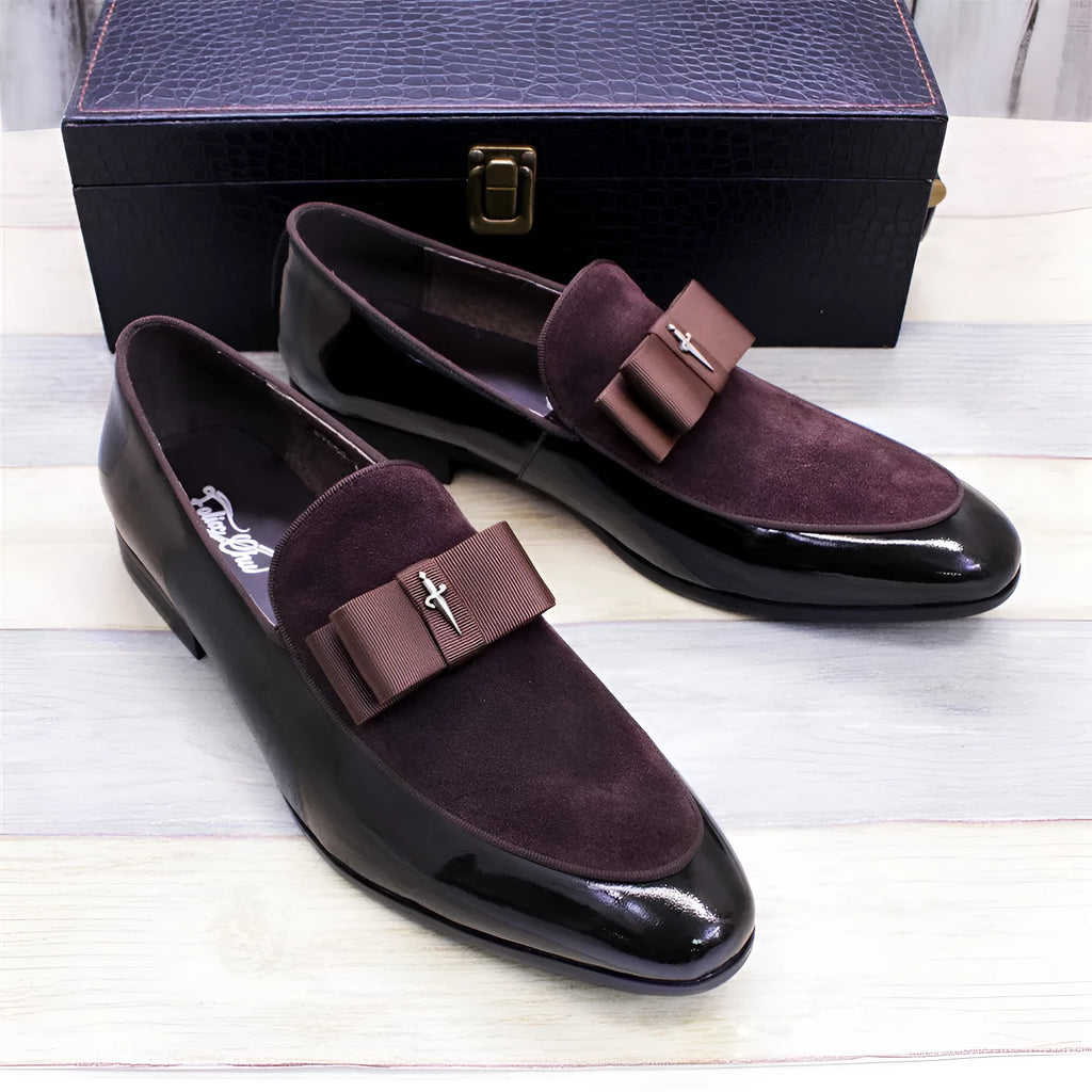 Men's black tassel loafer shoe with matte leather and glossy patent leather detail on a white background.