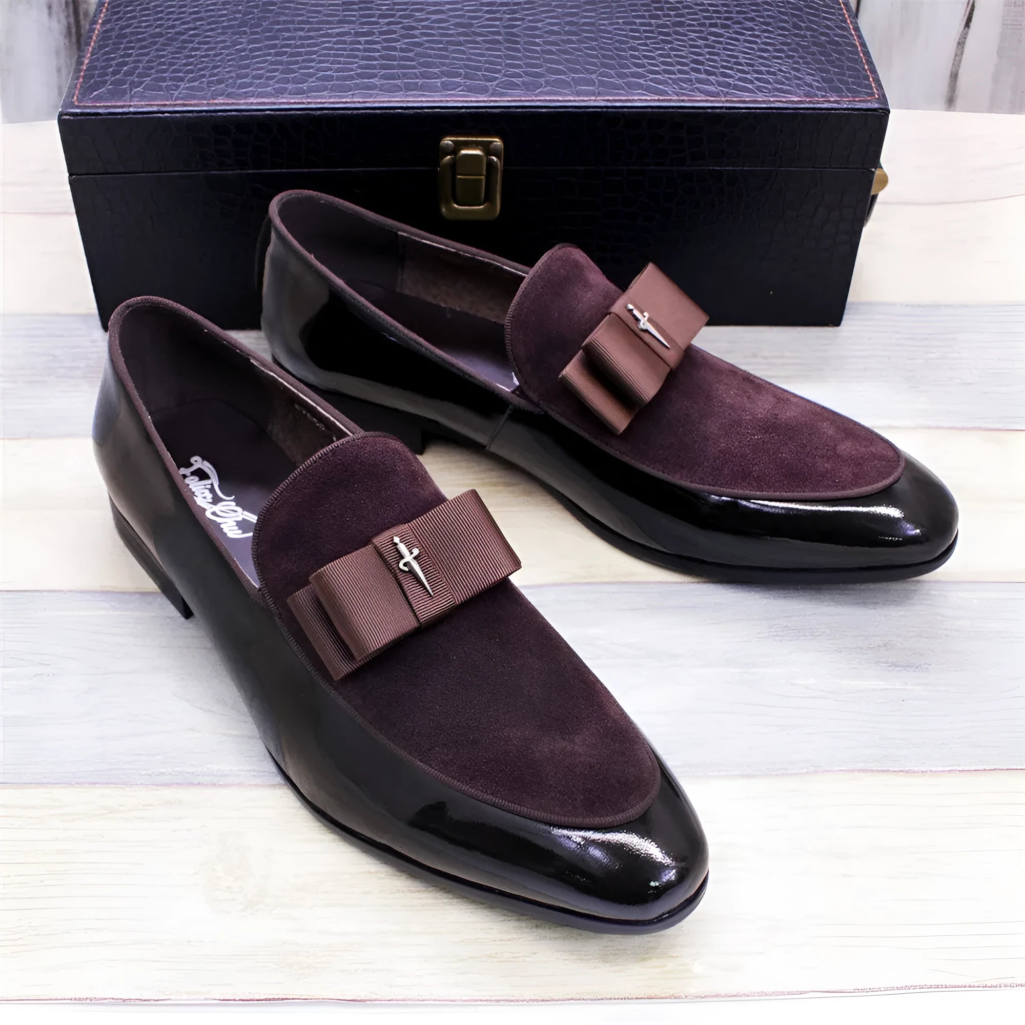 Men's black tassel loafer shoe with matte leather and glossy patent leather detail on a white background.