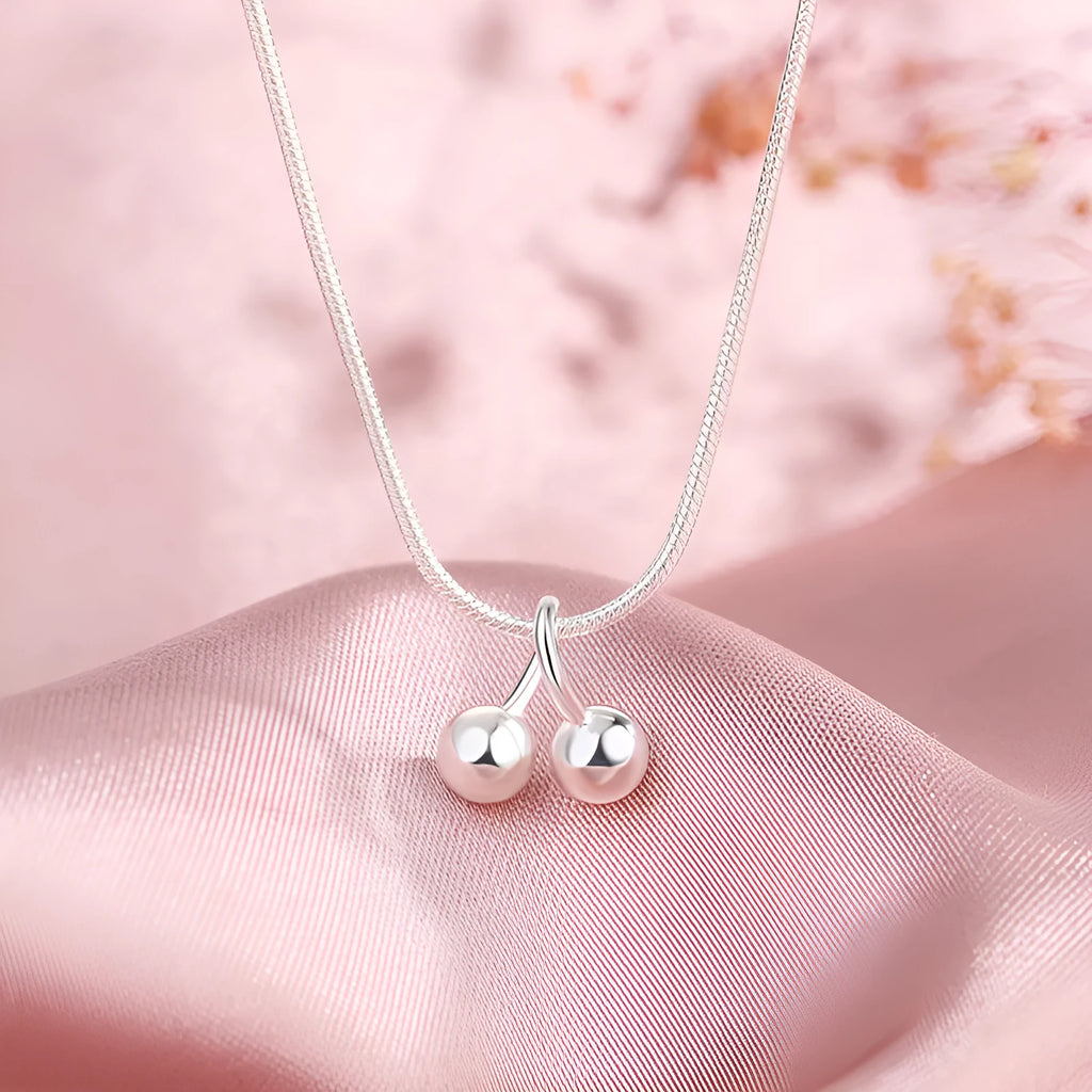 Close-up of a silver cherry pendant necklace on a textured snake bone chain, adjustable from 21cm to 50cm.
