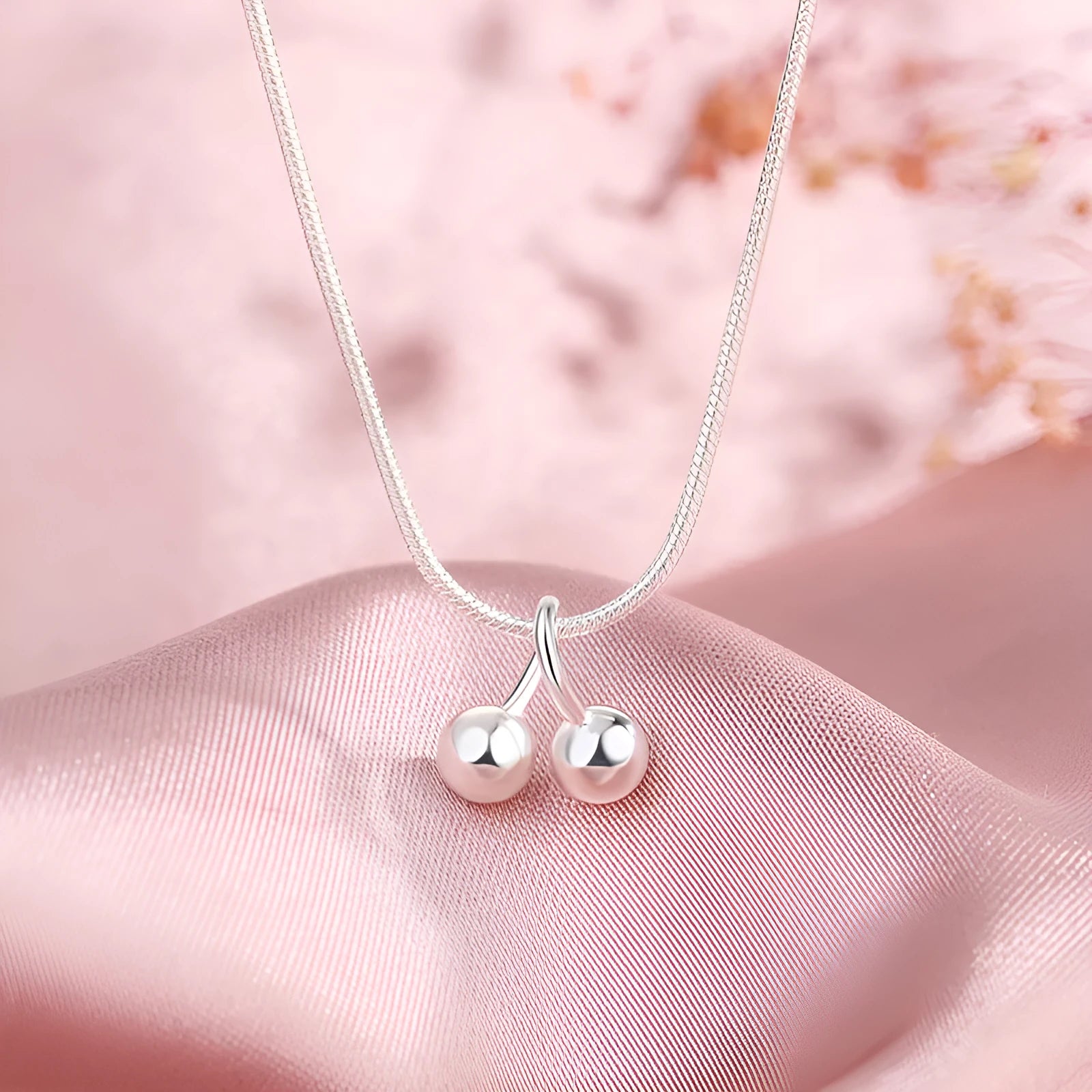 Close-up of a silver cherry pendant necklace on a textured snake bone chain, adjustable from 21cm to 50cm.