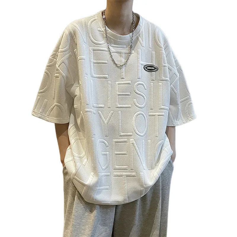 Man modelling a grey loose-fit T-shirt with a large retro-style graphic letter print on the front.